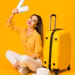smiley femme posant a cote des bagages tout en tenant des billets d avion